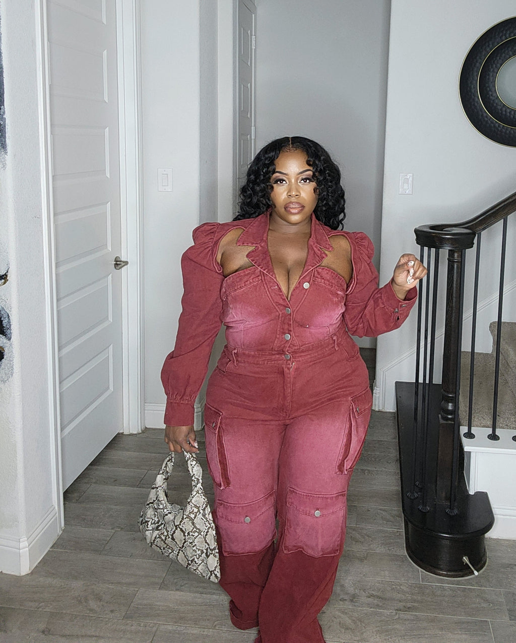 A person wearing a burgundy cutout corset jumpsuit with cargo pockets, standing indoors.
